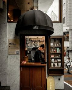 a man standing behind a counter in front of a store with an umbrella over it