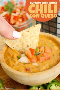 a hand dipping a tortilla chip into a bowl of chili con queso