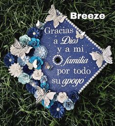 a blue graduation cap sitting on top of green grass with butterflies and flowers around it