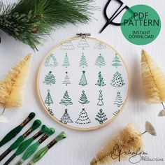 a cross stitch pattern with christmas trees on it and some crochet needles next to it