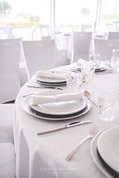 the table is set with silverware and white linens for an elegant dinner party