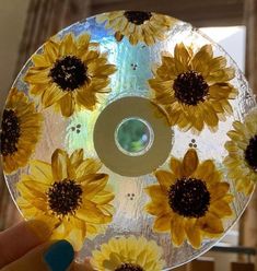 a person holding up a cd with sunflowers painted on the side and inside