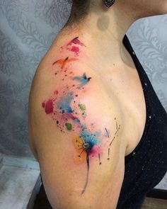 a woman's back shoulder with colorful paint splattered on it