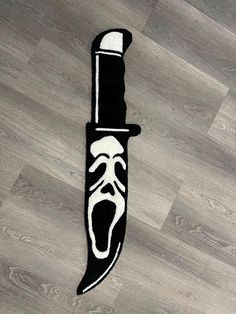 a black and white knife with an evil face on it's blade is laying on the floor