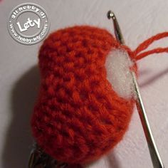 an orange crocheted object with a needle in it