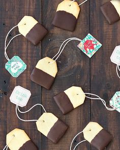 chocolate dipped marshmallows are tied up on a wooden table with tags attached to them