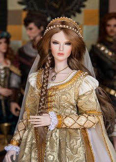 a doll dressed in gold and white with long braids on her head, standing next to other dolls