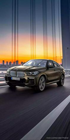 the new bmw x4 driving on a bridge at sunset with city lights in the background