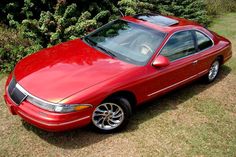 a red car parked in front of a bush