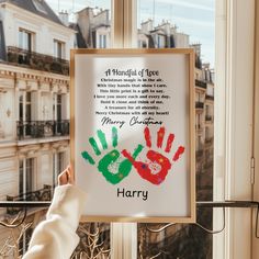 a person holding up a poster with their handprints on it in front of a window