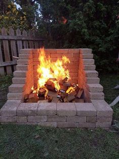 a brick fire pit sitting on top of a lush green field