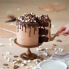 someone is cutting into a chocolate cake with marshmallows