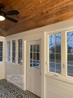 the inside of a house with two windows and a ceiling fan in front of it