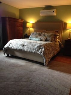 a bedroom with a bed, dressers and two lamps on either side of the bed