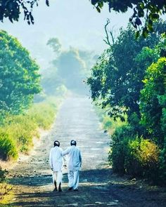 two people walking down a dirt road holding hands