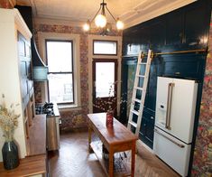 a kitchen with wooden floors and black painted walls, including a ladder leading up to the window