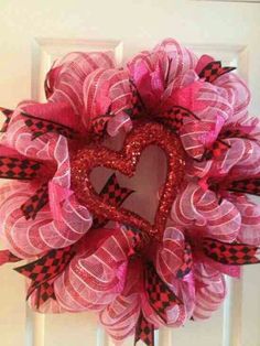 a pink and black wreath with a heart on the front door, hanging from a white door