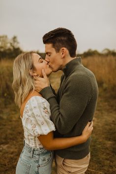 a man and woman kissing in an open field