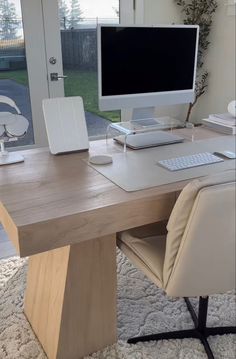 a desk with a computer, keyboard and mouse on it in front of a window