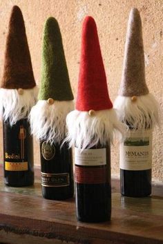 four wine bottles with gnome hats on them sitting on a shelf in front of a wall