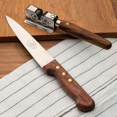 a large knife sitting on top of a wooden cutting board next to a knife sharpener