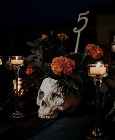 there is a skull with flowers in it and candles on the table next to it