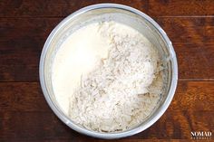 a metal bowl filled with rice on top of a wooden table