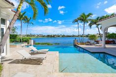 an outdoor swimming pool with lounge chairs next to it and palm trees in the background