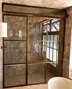 a bathroom with a glass shower door and tiled walls