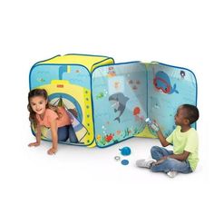 two children playing in a play tent with an ocean scene on the wall and dolphin theme