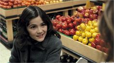 a woman standing in front of a display of fruits and vegetables