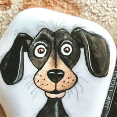 a painted rock with a dog's face on it