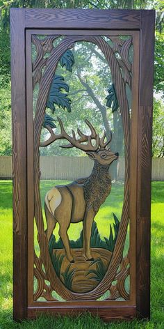 a wooden carving of a deer standing in the grass