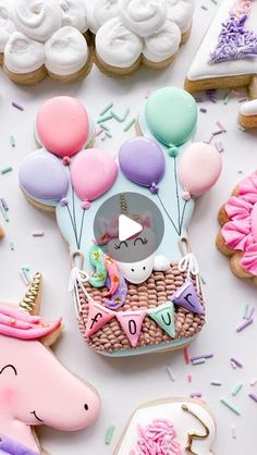 an assortment of decorated cookies and pastries on a white table with unicorns, balloons, and other items