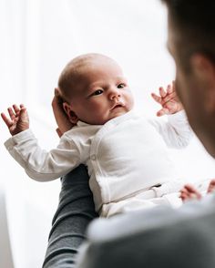 a woman holding a baby in her arms and touching it's head with both hands