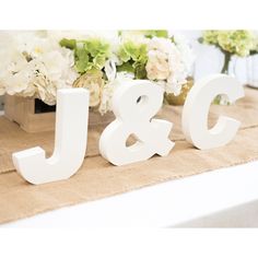 the letters j and c are white on top of a table with flowers in vases