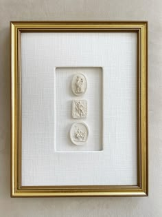 two white buttons in a gold frame on a wall