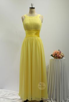 a yellow bridesmaid dress sitting on top of a table next to a flower vase