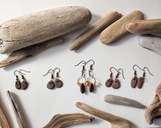 *Please read description before purchase! *Number of earrings will be on the top of each pair in the last picture. Please check your number before purchase. Thank you. Handmade with natural beach stone. Each pair is one-of-a-kind, featuring varying shapes, sizes, and tones of redish/brown. The pebbles are attached to brass hooks (nickel free), adding a touch of vintage charm. Choose from:  * Simple drop earrings with a single pebble  * Pebble pairs with amber bead accents These earthy earrings are perfect for adding a natural touch to any outfit, whether you're dressing up or down. Materials:  * Natural lake beach pebbles  * brass hooks  * Amber beads (where applicable) Care:  * To maintain the beauty of your earrings, avoid submerging them in water.  * Gently wipe clean with a soft cloth. Earthy Earrings, Tin Earrings, Beach Pebbles, Brass Hooks, Handmade Jewlery, Lake Beach, Antique Stone, Brass Antique, Beach Stones