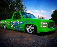 a bright green truck with flames painted on it's hood and tailpipes