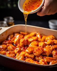 someone pouring sauce on chicken in a pan