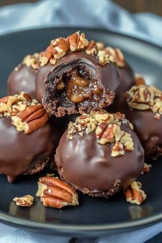 chocolate covered donuts with pecans and nuts in the middle on a black plate