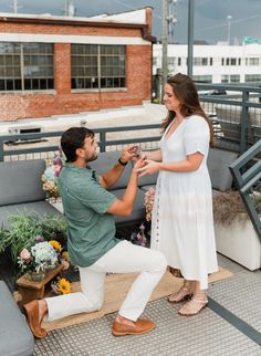 a man kneeling down next to a woman on top of a wooden bench with flowers