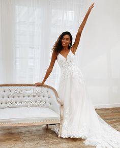 a woman standing next to a bed in a room with white walls and wooden floors