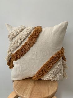 a white pillow with brown trim sitting on top of a wooden stool