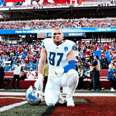 a football player kneeling on the field in front of an empty stadium filled with people