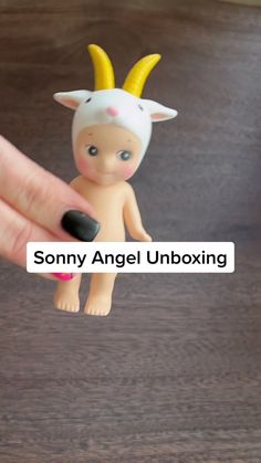 a hand holding a small toy with horns on it's head and the words, sony angel unboxing