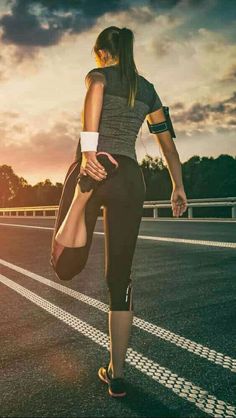 a woman is running on the road at sunset