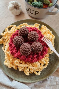 a crocheted dishcloth with four balls of yarn and a fork on it