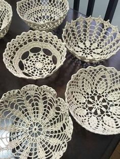 six white lace doily bowls on a table